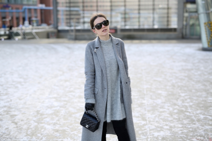 grey winter coat, cozy sweater, black purse, gloves, sunglasses