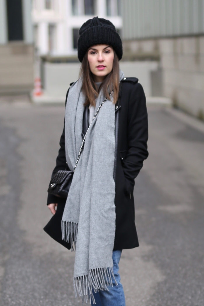 schwarze Beanie, grauer Schal, schwarzer Mantel, Jeans