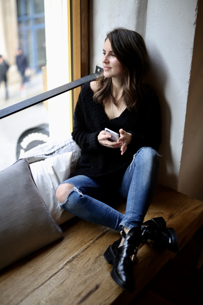 Fensterbank, Smartphone, schwarzer Pullover, Jeans, Balenciaga Boots