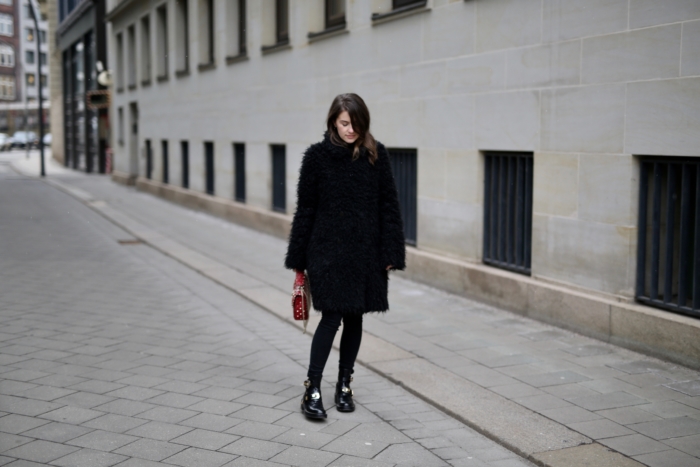 black furry coat, black pants, black Balenciaga boots, red Valentino purse