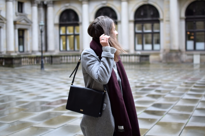 Schwarze Tasche, grauer Wollmantel, roter Schal