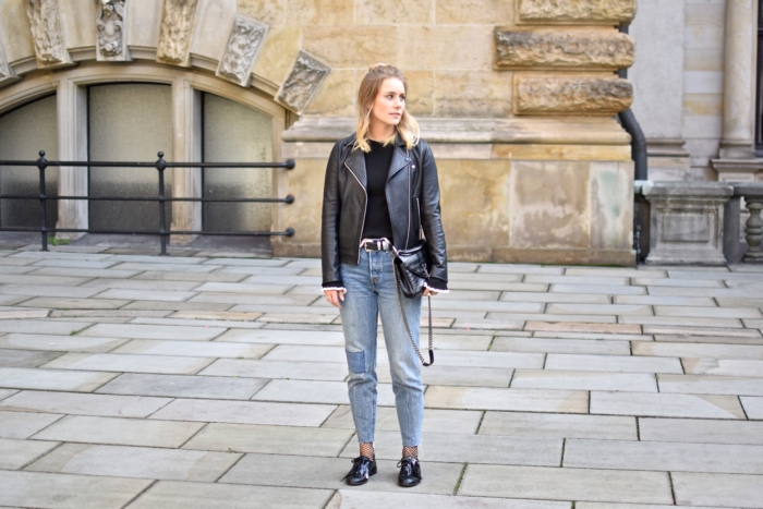High Waist Mom Jeans, Lederjacke, schwarzer Pullover mit Volantärmeln, Netzstrümpfe, Lackschuhe