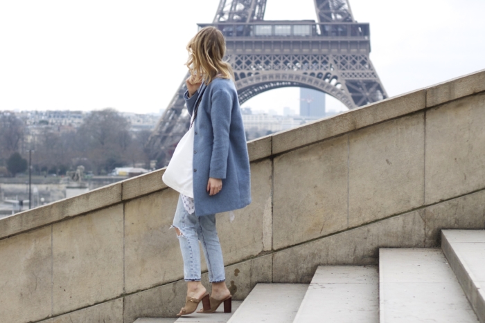 Paris, blauer Mantel, helle Jeans, weiße Bluse