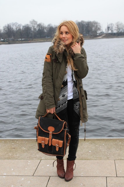 Khakifarbener Parka mit schwarzer Hose und braunschwarzer Tasche