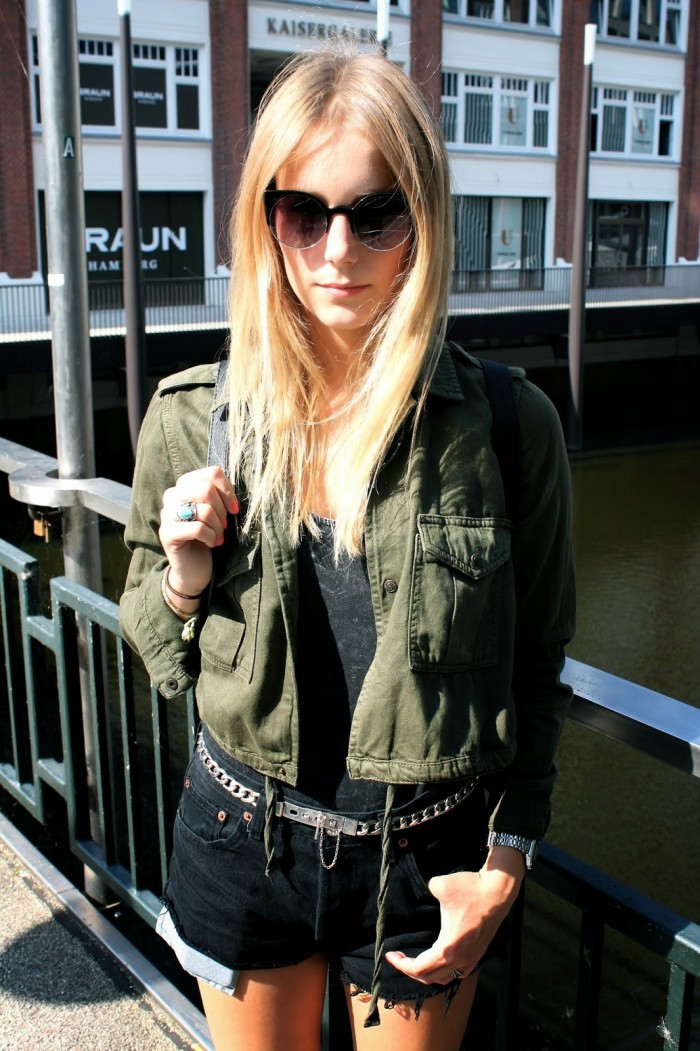 Khakifarbene Jacke mit schwarzem Top und schwarzer Hotpants, silberner Gürtel
