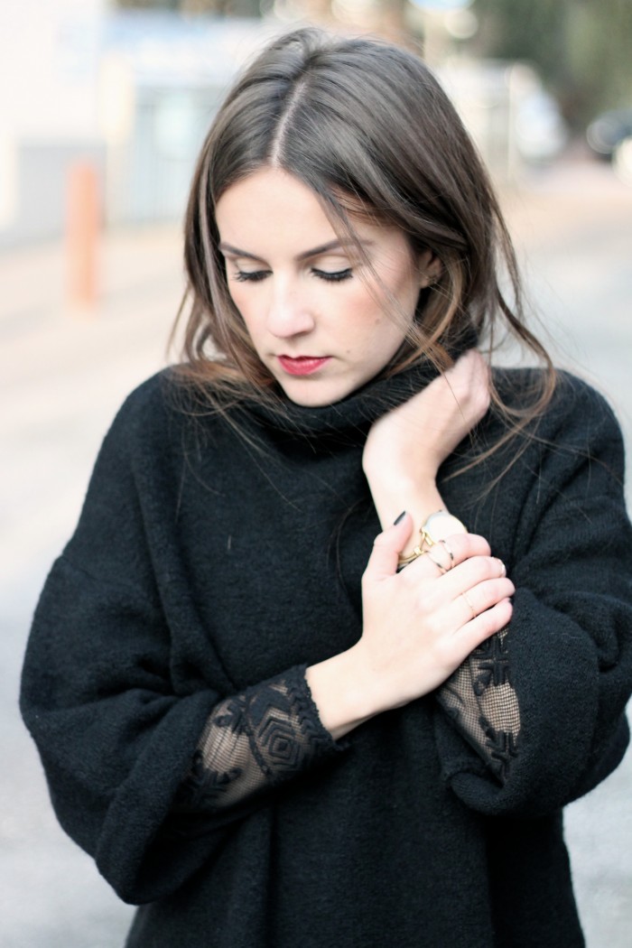 Schwarzes Spitzenoberteil unter schwarzem Pullover